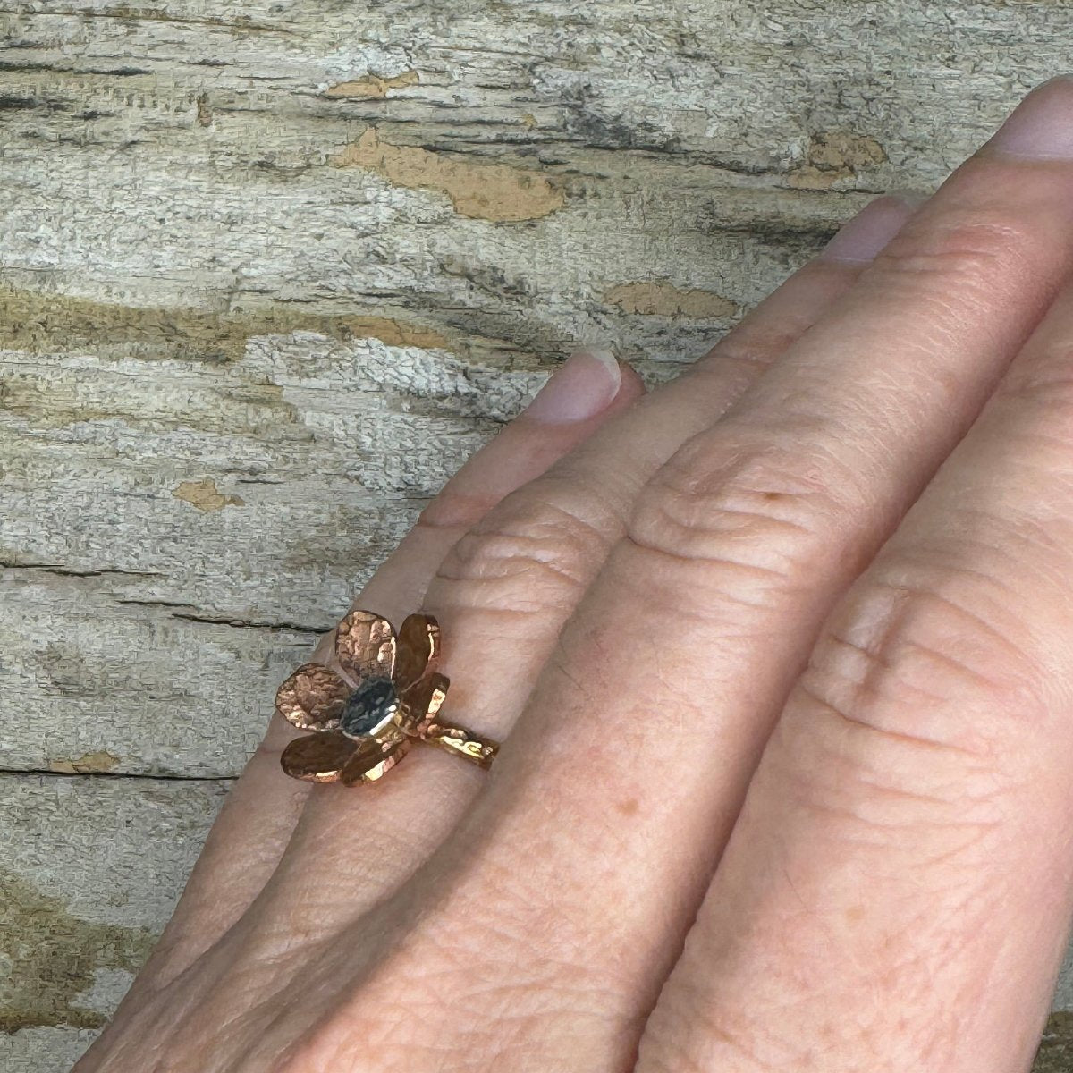 Artisan floret ring in copper, silver, and brass shown on hand, boho-inspired jewelry with floral detailing