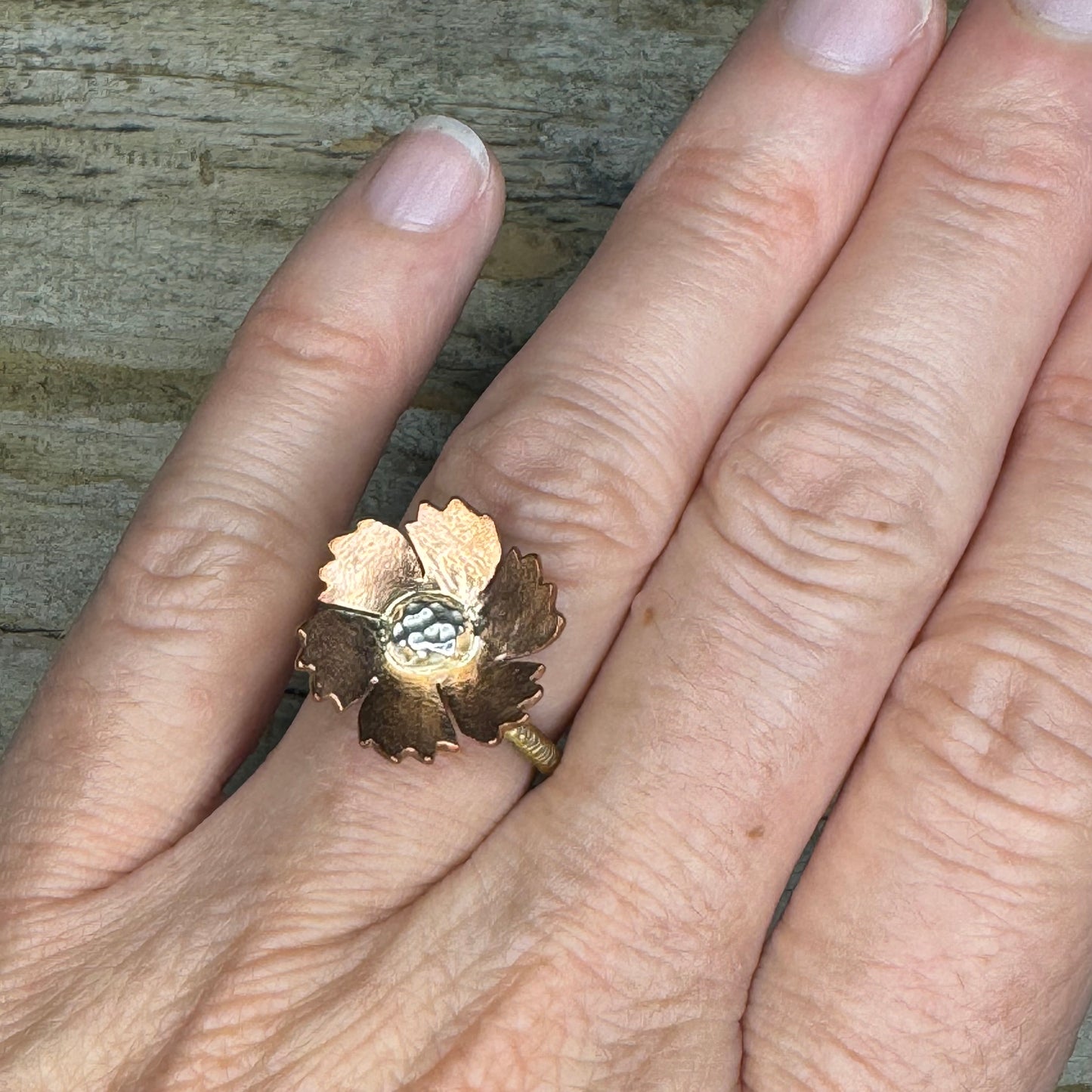Hand wearing floral-inspired mixed metal ring in copper, silver, and brass, lightweight and artisan-crafted