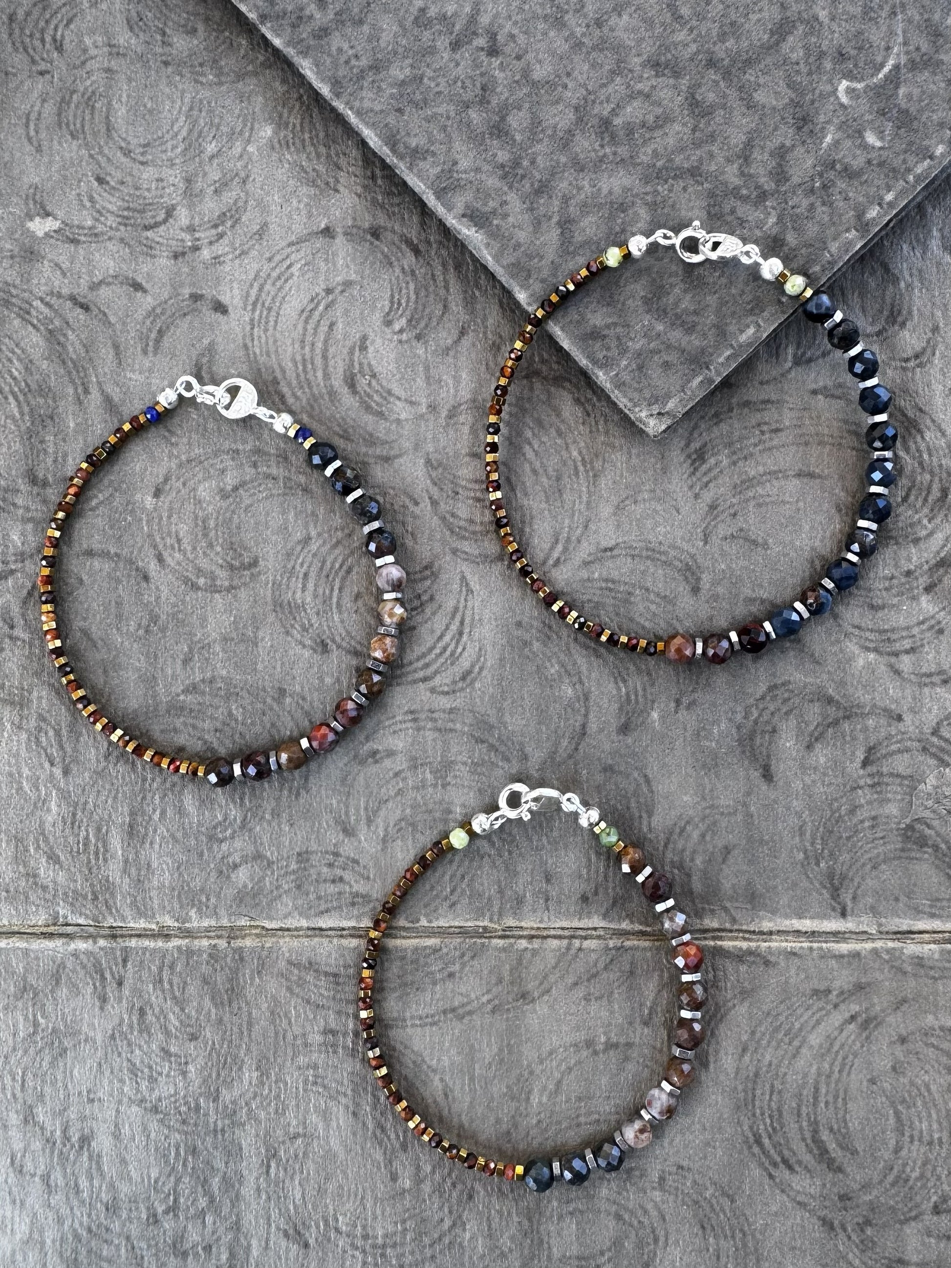Three beaded bracelets on a textured gray surface