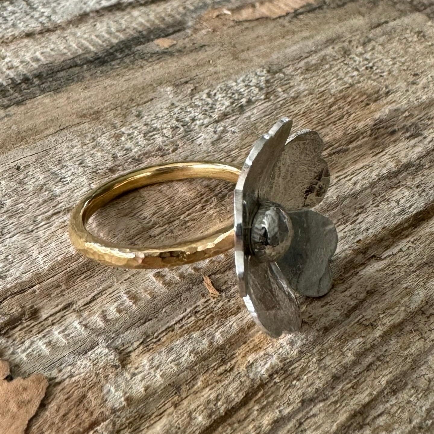 Detailed view of sterling silver floral centerpiece on textured brass band, handmade rustic ring