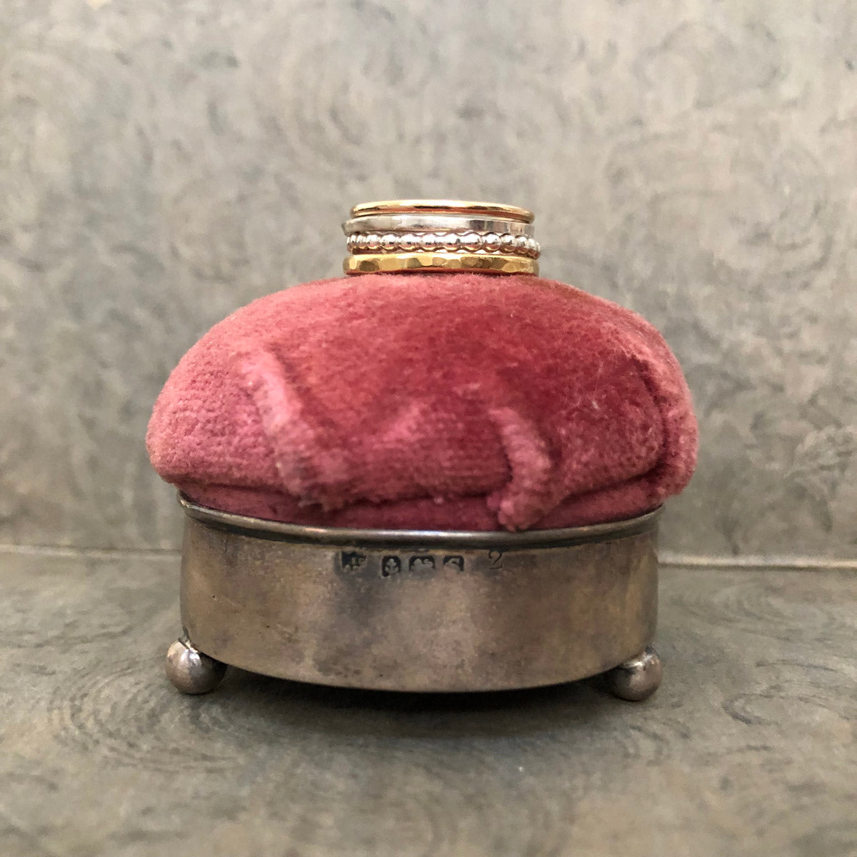 Alpine Loop stacking ring set—four mixed metal rings stacked on a pink velvet pin cushion, featuring brass, gold-filled, and sterling silver textures by Narrow-Gauge Designs