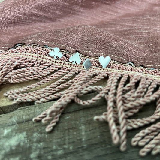 Pharo sterling silver card suit earrings—Heart, Spade, Club, and Diamond—nestled on a mauve fringed tablecloth.