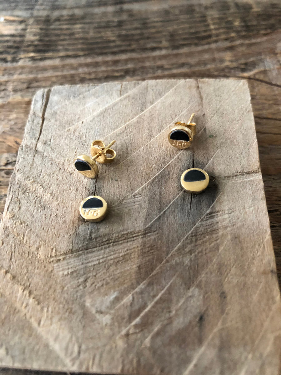 Two pairs of Holliday Black Jade stud earrings displayed on rustic wooden background, highlighting their handcrafted elegance and duality.