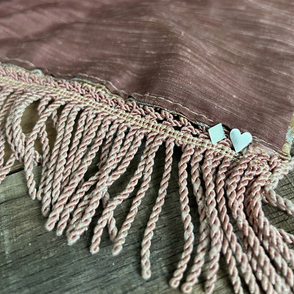 Pharo sterling silver Diamond and Heart card suit earrings resting on a mauve fringed tablecloth